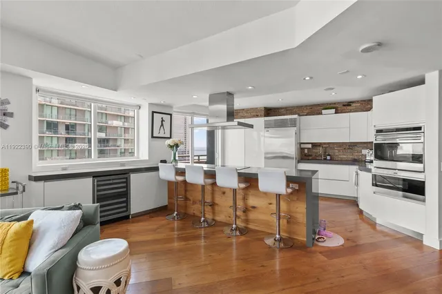 a kitchen with stainless steel appliances kitchen island granite countertop a table chairs and a refrigerator