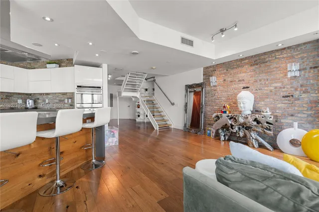 a living room with couches and kitchen view with wooden floor