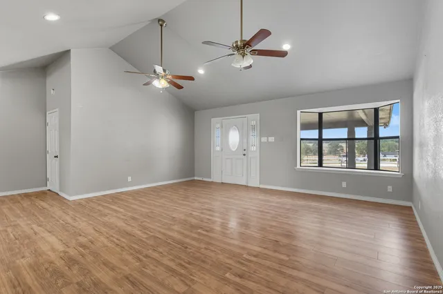 a view of an empty room with a window and wooden floor