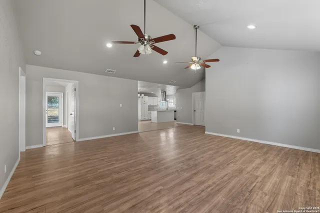 a view of empty room with wooden floor and ceiling fan