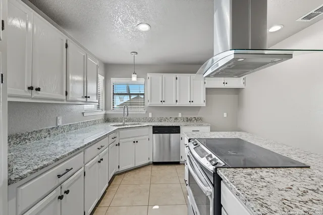 a kitchen with granite countertop a sink a stove and cabinets