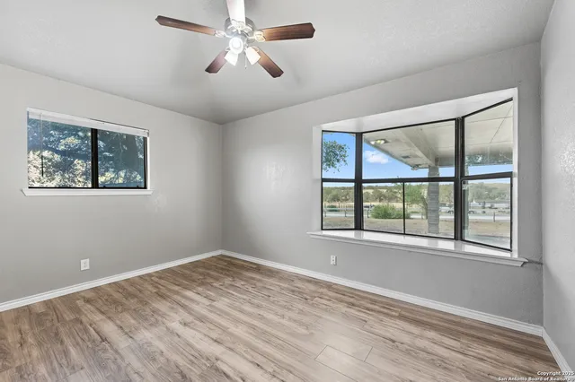 a view of empty room with wooden floor and fan