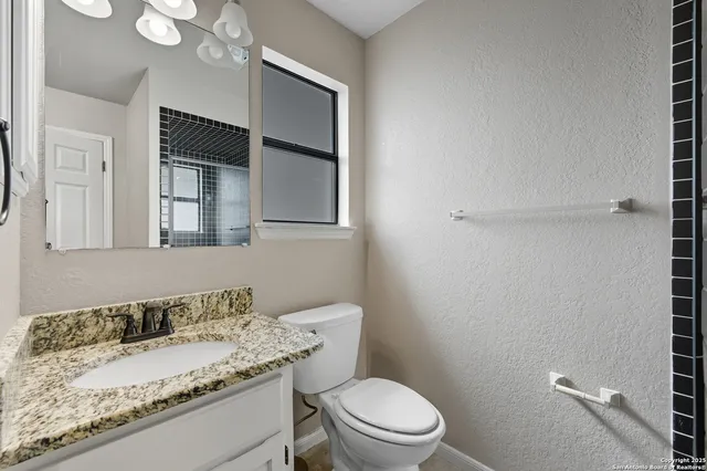 a bathroom with a granite countertop sink a toilet and mirror