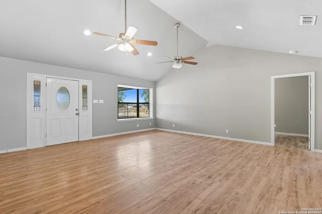 a view of an empty room with window and wooden floor