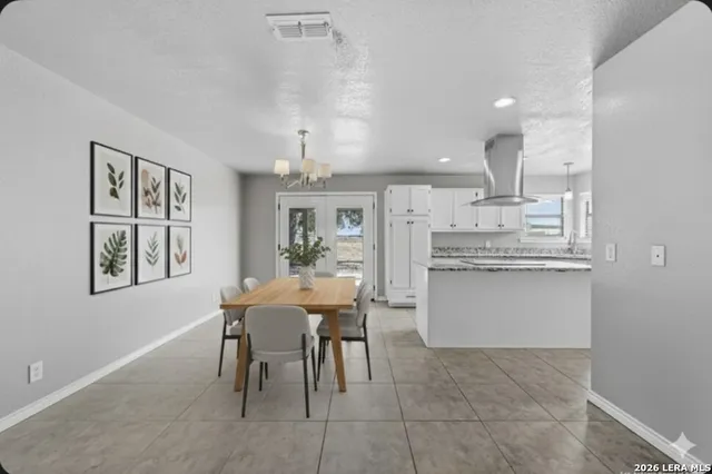 a dining room with kitchen island stainless steel appliances furniture a chandelier and kitchen view