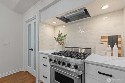 a kitchen with a stove and a wooden floor