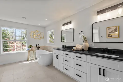 a spacious bathroom with a granite countertop sink a large mirror a bathtub and window