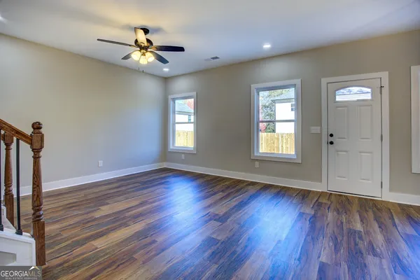 a view of an empty room with wooden floor and a window