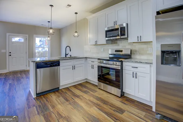 a kitchen with stainless steel appliances granite countertop a stove a sink and a microwave
