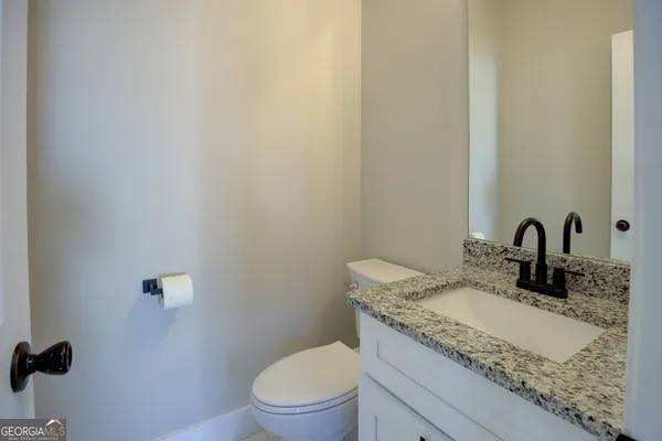 a bathroom with a granite countertop toilet sink and mirror