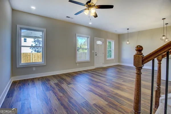 a view of an empty room with wooden floor and a window