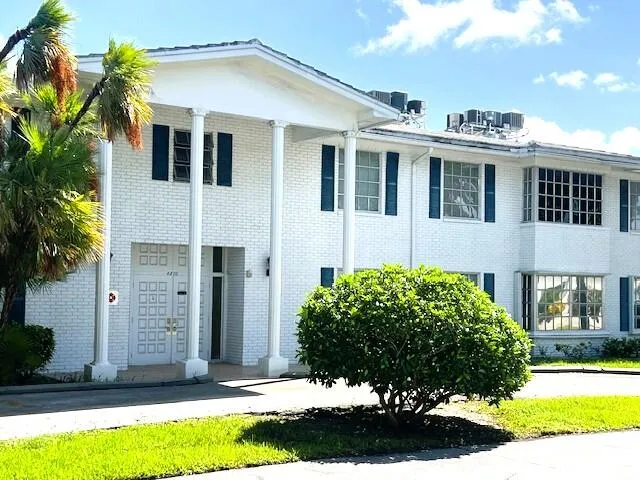 a view of a white house with a large windows and a yard with plants