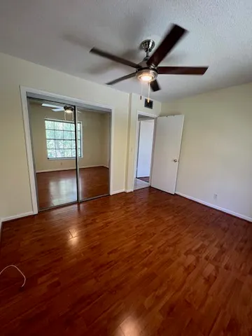 an empty room with wooden floor ceiling fan and windows