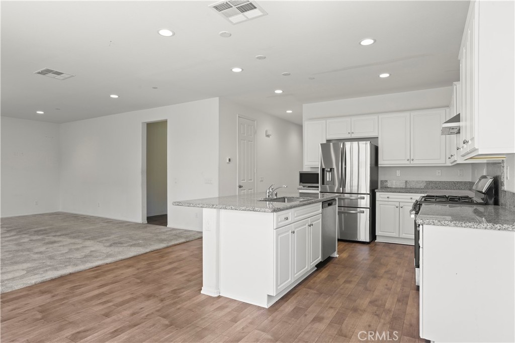 3320 Jack Rabbit Court Perris, CA 92570 - Photo 13 of 42 a kitchen with stainless steel appliances granite countertop a refrigerator sink stove oven and white cabinets
