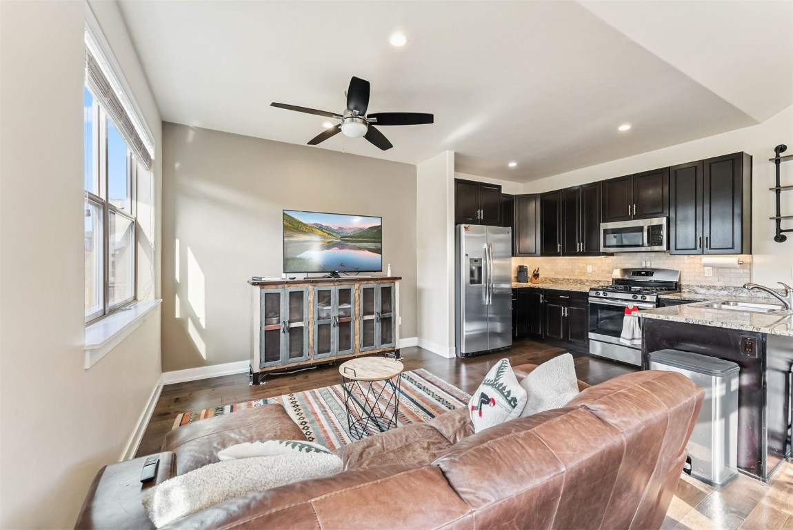 a living room with stainless steel appliances furniture a rug and a kitchen view