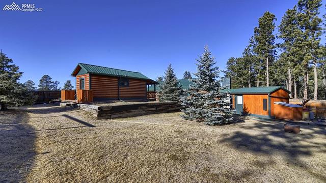 6475 Burrows Road Colorado Springs, CO 80908 - Photo 9 of 30 Fully Fenced yard within the 1.35 areas. landscaped with blue spruce and maintained with care. Potential tiny home on the left and the other storage unit with generator to the right. Main house in the middle behind the spruce trees.