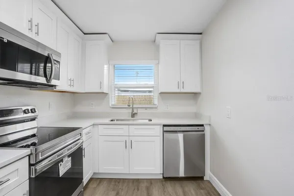 a kitchen with stainless steel appliances granite countertop white cabinets a sink and dishwasher