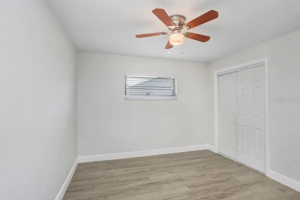 an empty room with wooden floor and ceiling fan