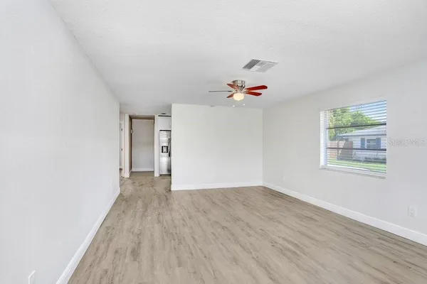 a view of an empty room with wooden floor and a window