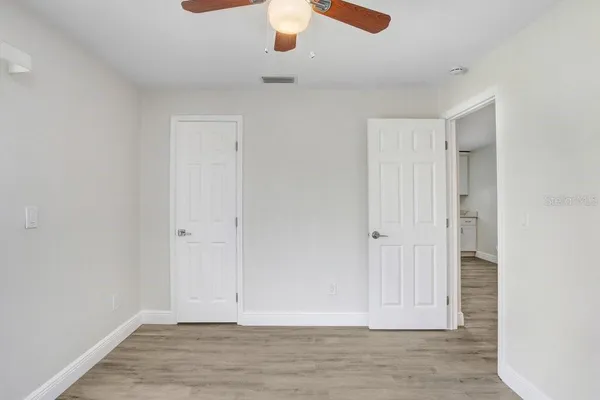 an empty room with wooden floor closet and windows