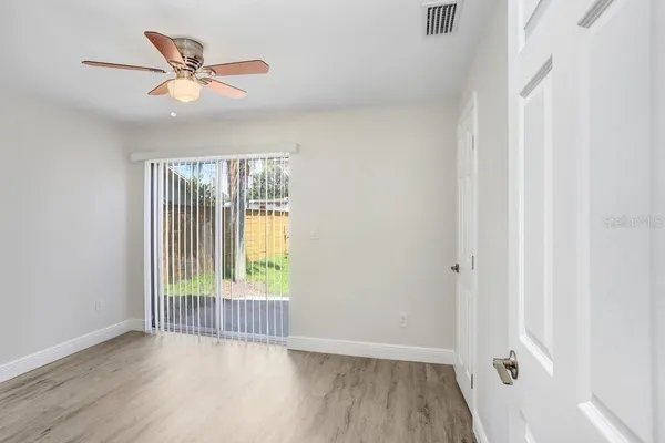 a view of an empty room with wooden floor and a window