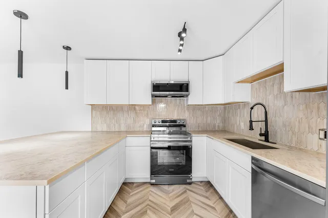 a kitchen with stainless steel appliances granite countertop a sink a stove and a refrigerator