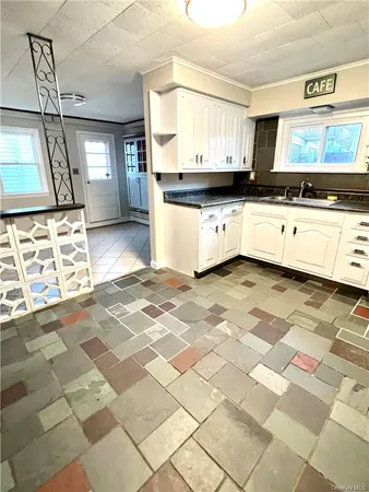 a large kitchen with granite countertop a stove a sink a window and cabinets