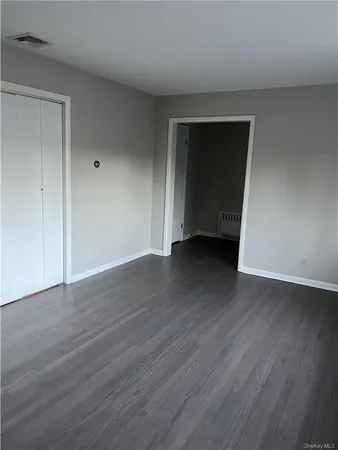 a view of an empty room with wooden floor and closet