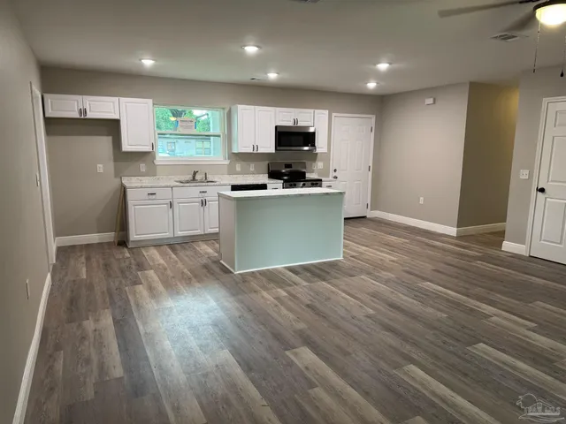 a kitchen with stainless steel appliances kitchen island granite countertop a stove a sink and a refrigerator