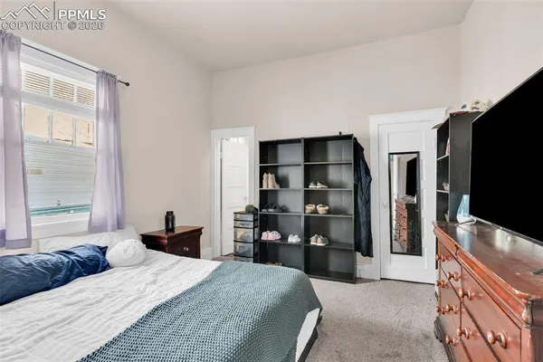 a bedroom with a bed and a flat tv screen on dresser