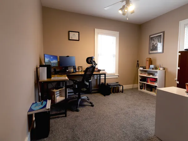 a view of a workspace room with furniture and a window