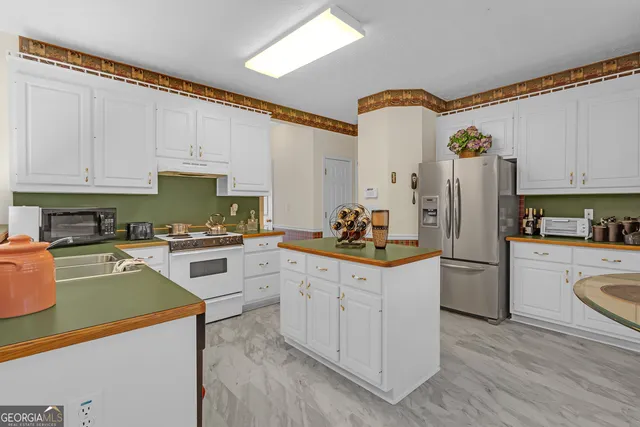 a kitchen with a refrigerator a stove a sink dishwasher and white cabinets with wooden floor