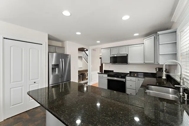 a kitchen with stainless steel appliances granite countertop a refrigerator a stove and a sink