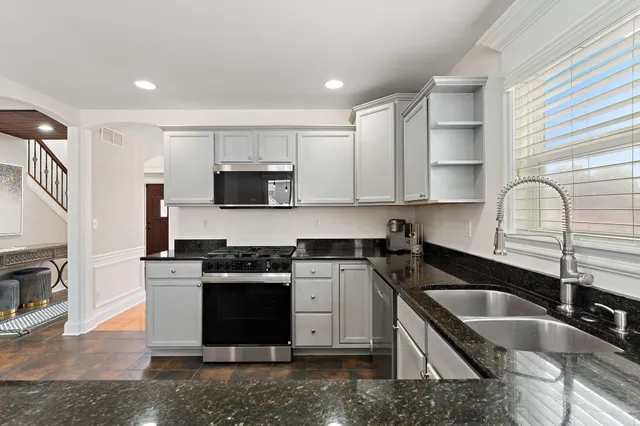 a kitchen with granite countertop a sink a stove and refrigerator