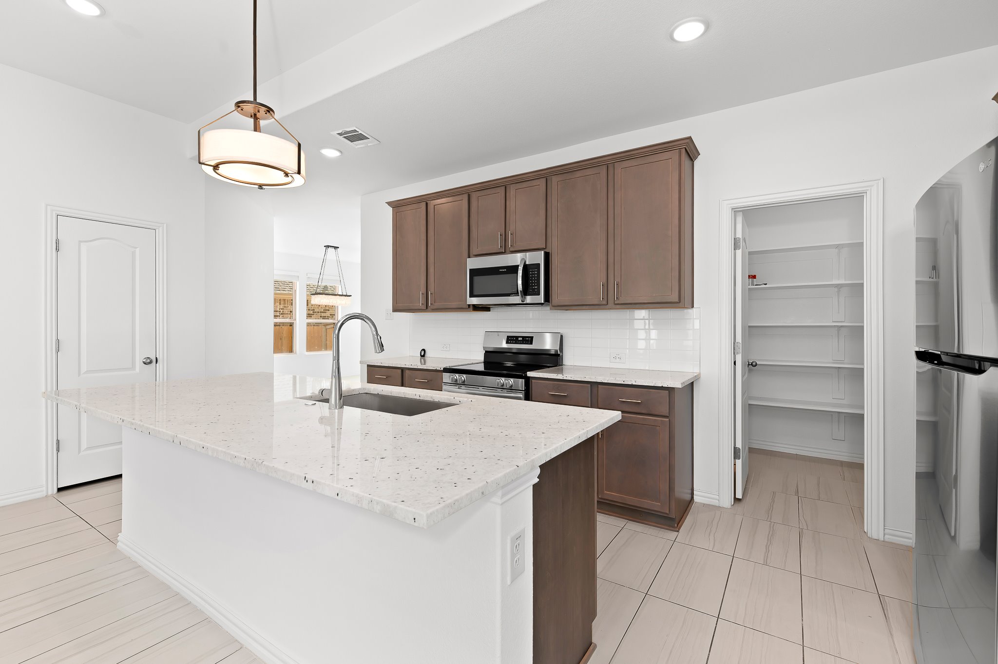 1128 Ridge Runner Drive Georgetown, TX 78628 - Photo 12 of 40 Kitchen featuring stainless steel appliances, light stone counters, pendant lighting, a center island with sink, and tasteful backsplash