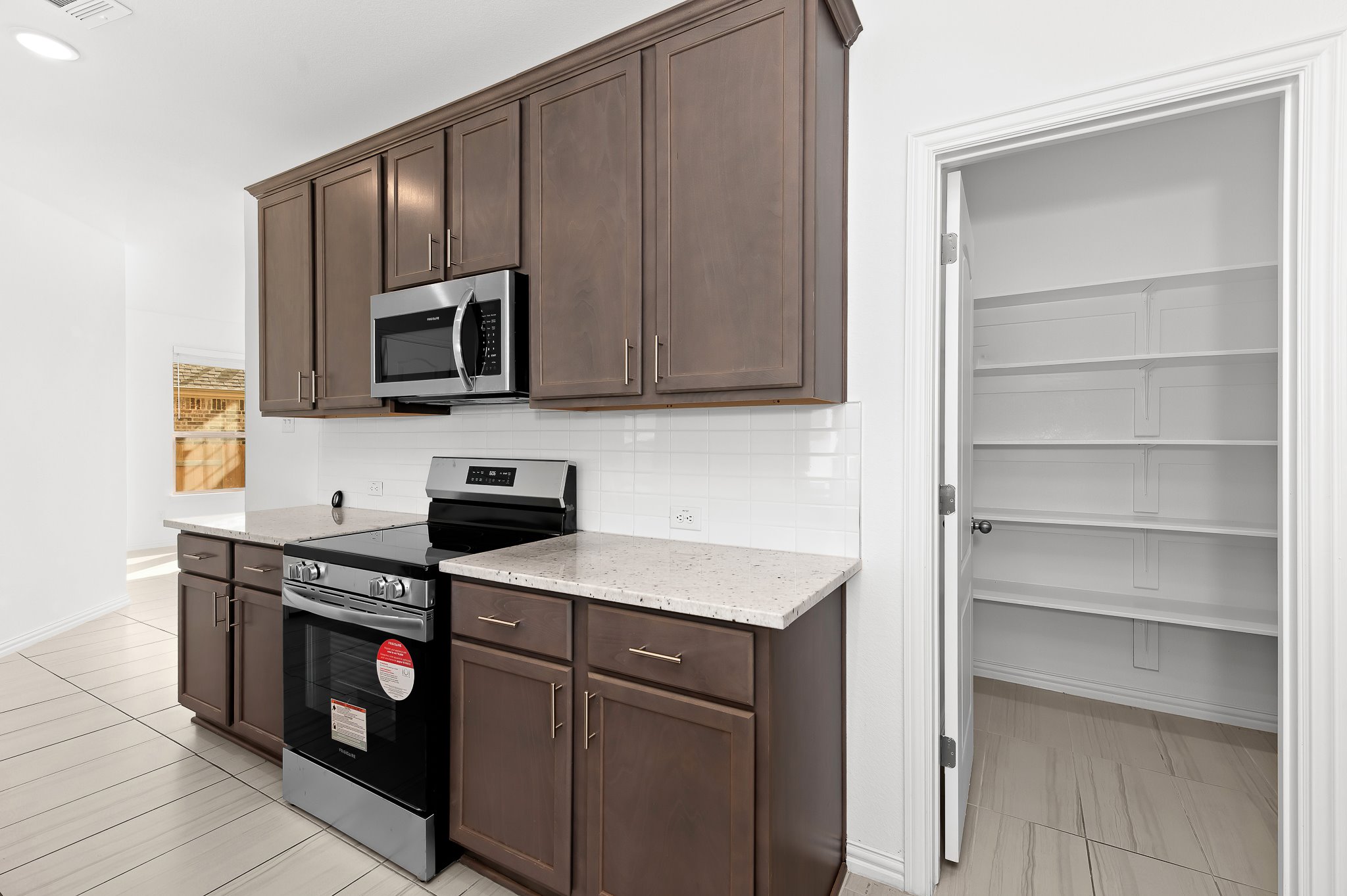 1128 Ridge Runner Drive Georgetown, TX 78628 - Photo 13 of 40 Kitchen with dark wood finish cabinets, stainless steel appliances, light stone counters, and tasteful backsplash