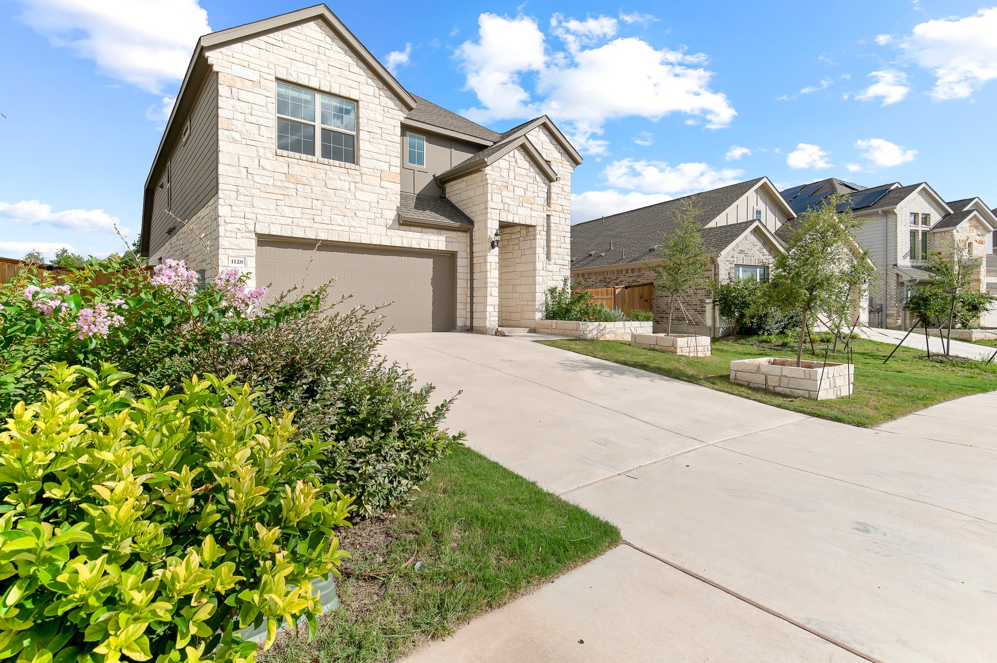 1128 Ridge Runner Drive Georgetown, TX 78628 - Photo 2 of 40 View of front of property with stone siding, an attached garage, concrete driveway, and a front lawn