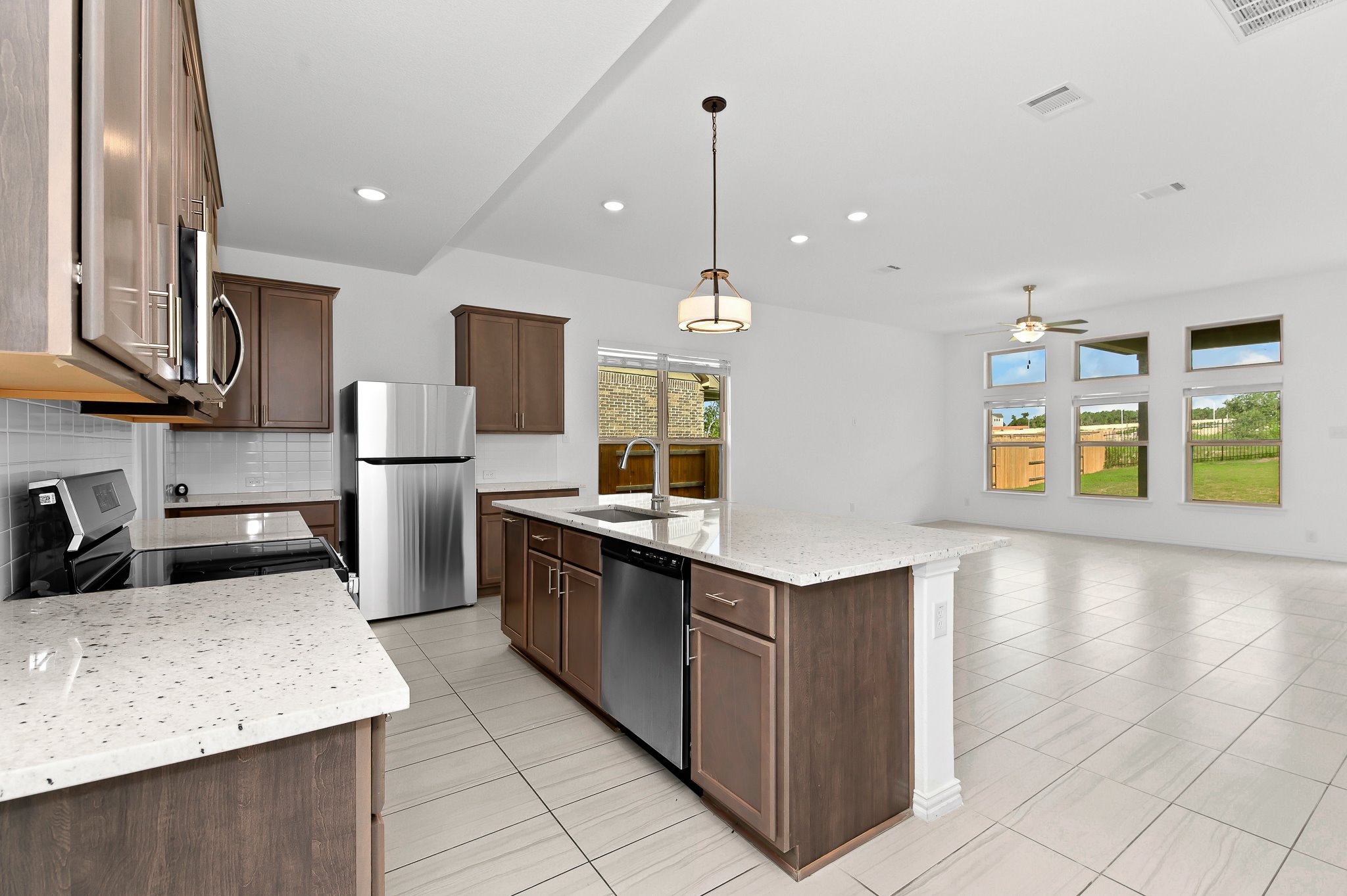 1128 Ridge Runner Drive Georgetown, TX 78628 - Photo 38 of 40 Kitchen featuring light stone counters, stainless steel appliances, open floor plan, decorative backsplash, and hanging light fixtures