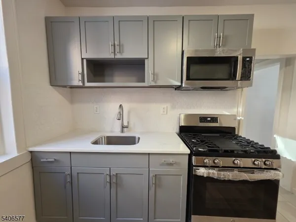 a kitchen with stainless steel appliances a stove a microwave a sink and cabinets