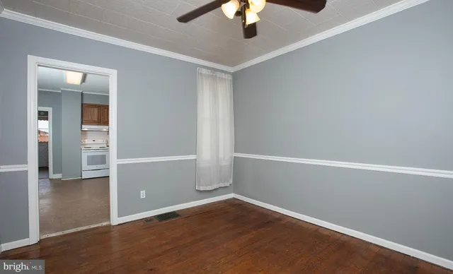 an empty room with wooden floor and fan
