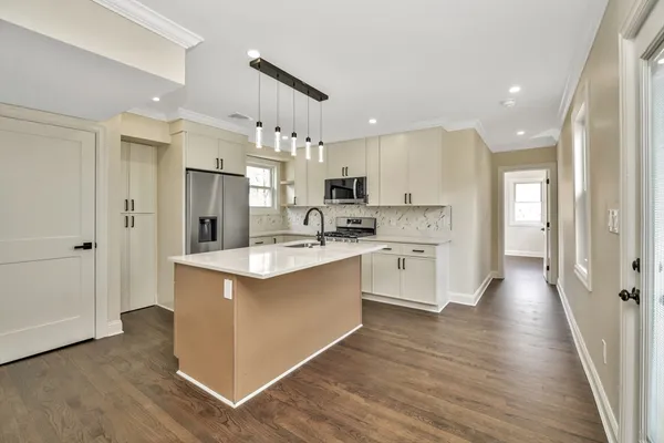 a large kitchen with stainless steel appliances kitchen island a large counter top and a wooden floors