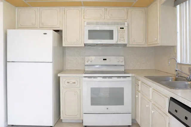 a kitchen with white cabinets and white appliances