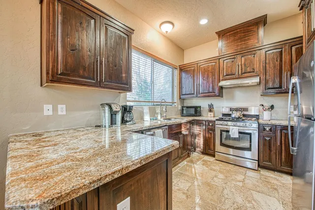 a kitchen with kitchen island granite countertop a sink stove and refrigerator