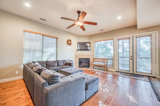 a living room with fireplace furniture large windows and wooden floor