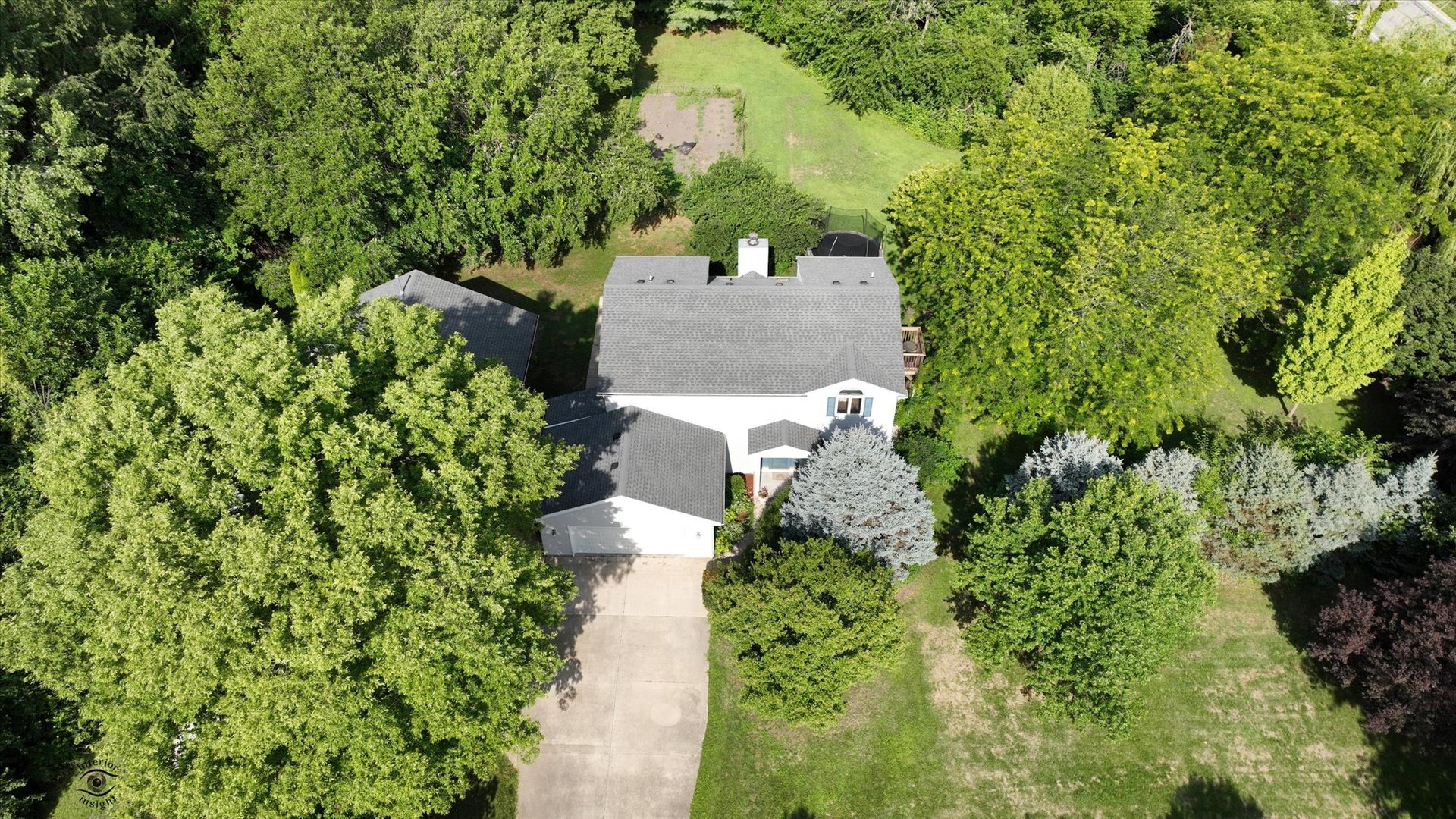 an aerial view of a house with a yard and trees all around
