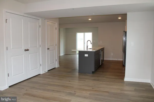 a view of kitchen and empty room with wooden floor