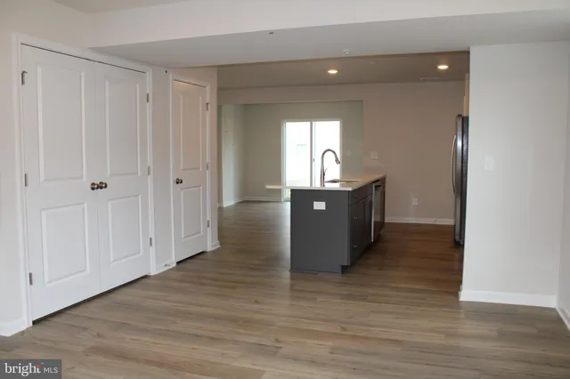 a view of kitchen and empty room with wooden floor