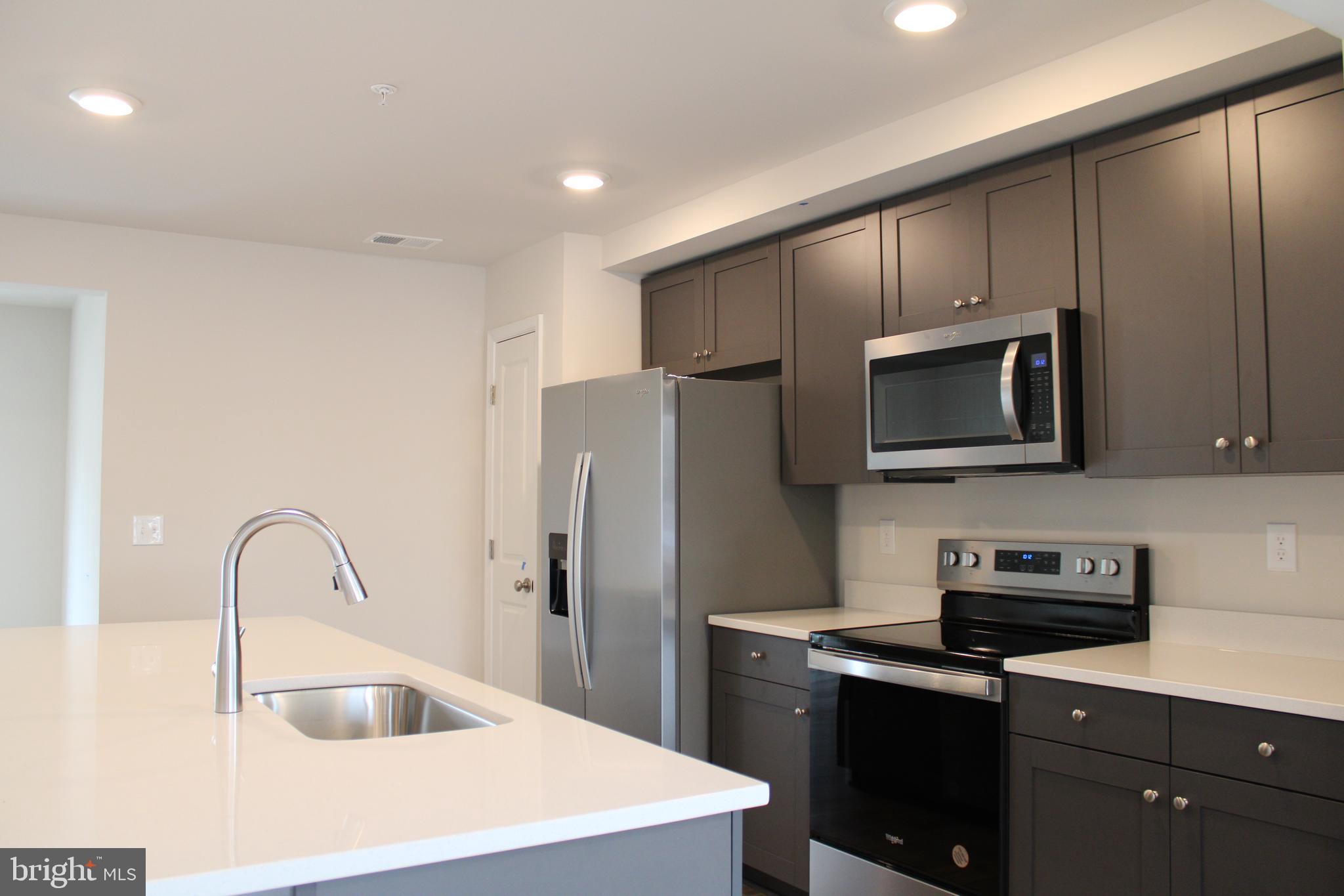 517 Merganser Way Cambridge, MD 21613 - Photo 5 of 13 a kitchen with stainless steel appliances granite countertop a sink a stove a refrigerator a microwave and cabinets