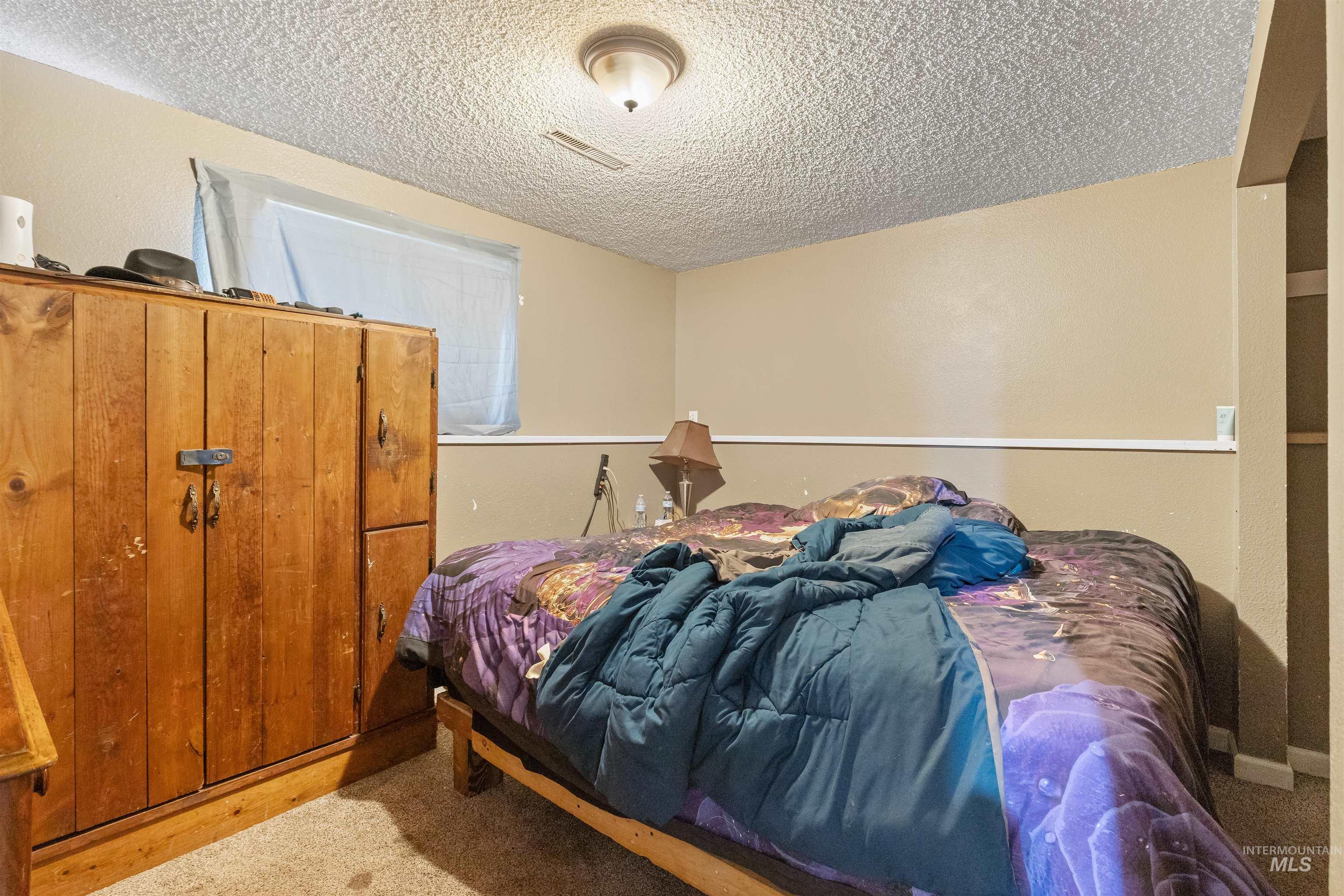 2460 State Street Pomeroy, WA 99347 - Photo 13 of 18 Carpeted room featuring a window with a valance, textured ceiling, and a wall-mounted light fixture