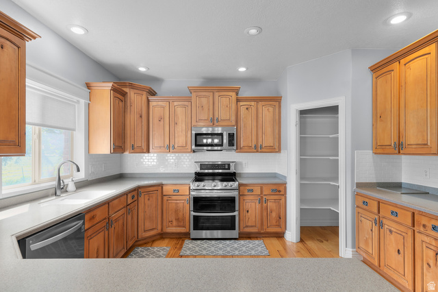 1501 West Elk Circle Mapleton, UT 84664 - Photo 18 of 39 Kitchen featuring wood cabinetry, light countertops, subway tile backsplash, stainless steel appliances, and wood-finish flooring